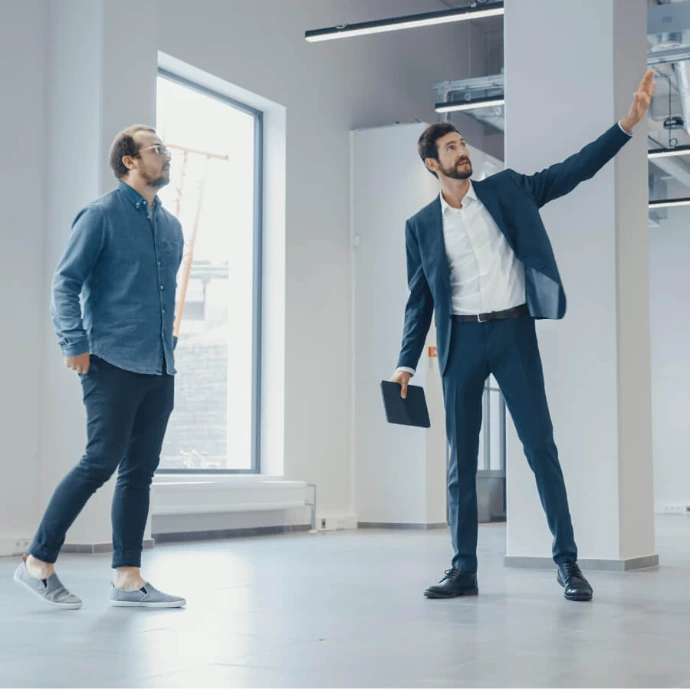 Two people discussing inside a building, representing real estate sector